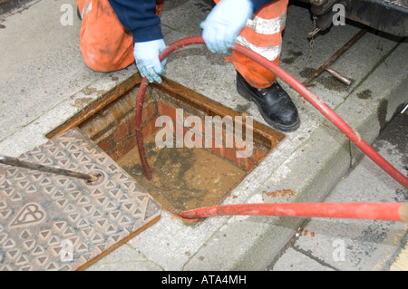 A Dyno rod worker drain clearing blocked drain outside a terraced house ...
