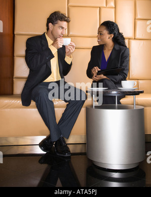 Caucasian businessman and African Amerian woman drinking coffee Stock Photo