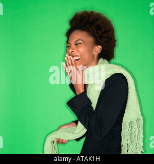 Pretty woman wearing green scarf laughing against green background Stock Photo