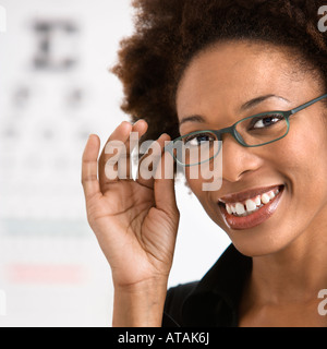 Portrait of woman with afro wearing eyeglasses with medical eyechart in background Stock Photo