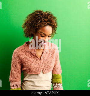 Portrait of pretty young woman standing against green background laughing Stock Photo