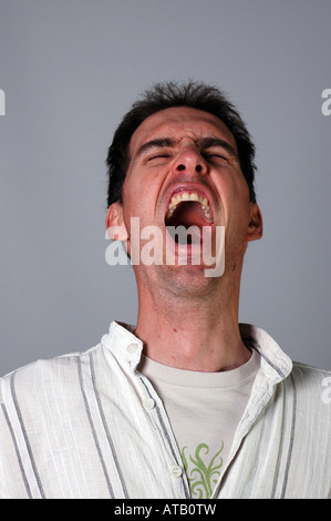 Casually dressed young man yawning with fatigue Or is he screaming and yelling? Stock Photo