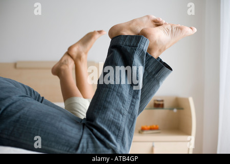 The legs of two persons lying next to each other on a bed Stock Photo