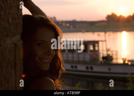 cute brown-haired woman smiling, with a ship on the river in the background Stock Photo