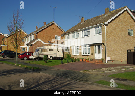 Village residential street of mainly semi detached houses with front drives used for car & caravan parking no garden walls Stock Photo