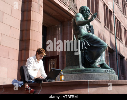 A young student working on her laptop in front of the University of Freiburg, Germany Stock Photo
