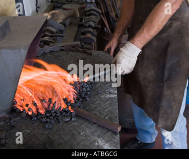 Old style hand made iron workers in a small work shop heating the iron rod before shaping Stock Photo
