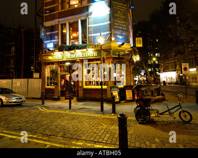 Rickshaw tricycle driver relaxing in front of a Soho pub on a quiet night London UK Stock Photo