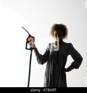 Woman holding gasoline pump nozzle against white background with dramatic studio lighting Stock Photo