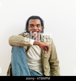 Portrait of man sitting against white background smiling Stock Photo