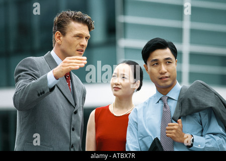 Business associates standing outdoors, talking, man gesturing with hand Stock Photo