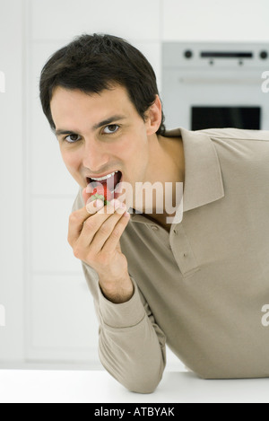 Man eating strawberry, looking at camera, close-up Stock Photo