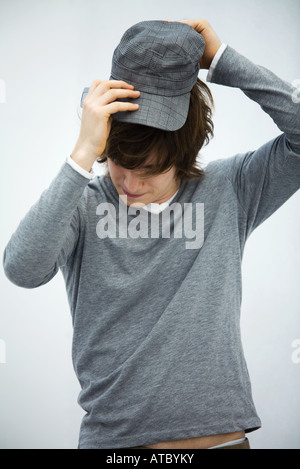 Young man putting on cap, head down, close-up Stock Photo