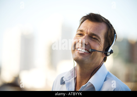 Businessman using headset, smiling, close-up Stock Photo
