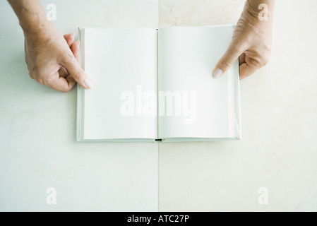 Cropped view of hands holding open book, viewed from directly above Stock Photo