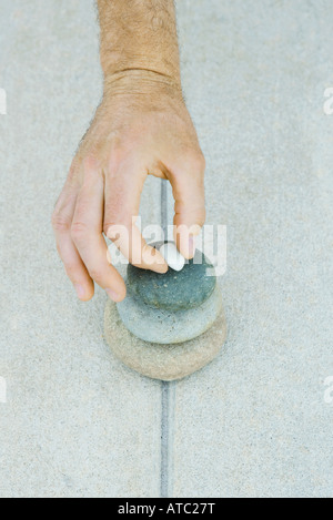 Man stacking pebbles, cropped view of hand Stock Photo