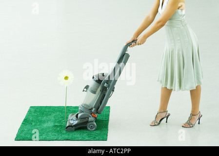 Woman vacuuming square of artificial turf, chest down Stock Photo