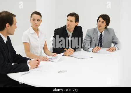 Team of professionals sitting together at table, discussing, looking at each other Stock Photo