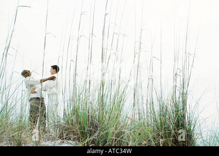 Two men embracing outdoors, low angle view through tall grass Stock Photo