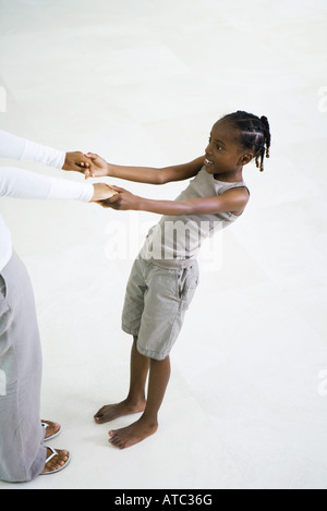 Little girl holding mother's hands, leaning back, cropped view Stock Photo