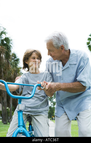 Grandfather teaching grandson to ride bicycle, front view Stock Photo