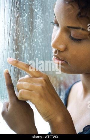 Mother and child touching rain streaked window, cropped view Stock Photo