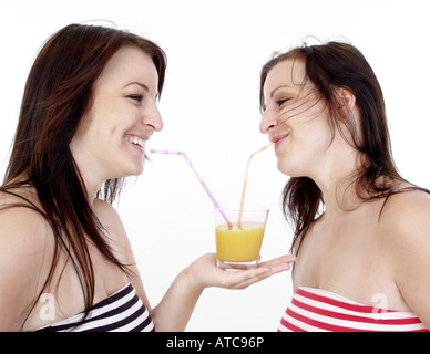 twins drinking orange juice with straws Stock Photo