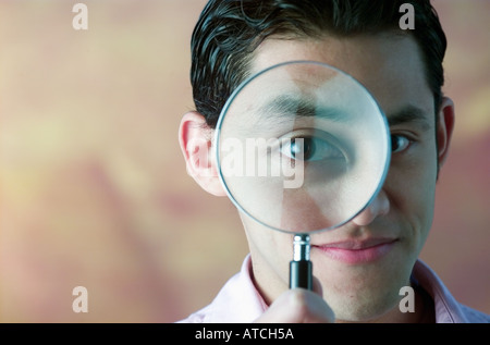 Portrait Mixed Race Man holding magnifying glass Stock Photo