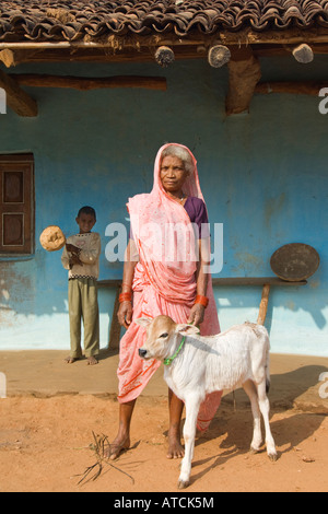 Indian Farmer Woman wearing a pink dress and holding a cow in front of ...