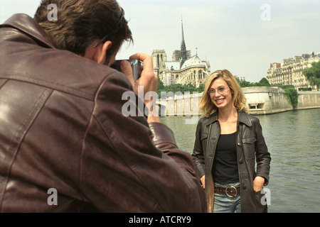 Man taking photographs of woman, Notre-Dame in background, Paris, France Stock Photo