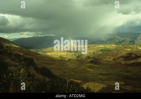 A rainbow appearing through the mist of rain clouds over agricultural patchworks in Cusco, Peru Stock Photo