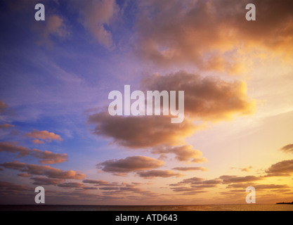 A brilliant evening sky of blue yellow and pink illuminates the sea Stock Photo