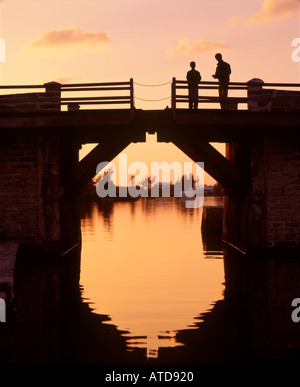 Sunset silhouette of people on the worlds smallest drawbridge footbridge in Bermuda Stock Photo