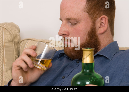 depressed tired alcoholic young man drinking whisky alcohol spirits looking thoughtful Stock Photo