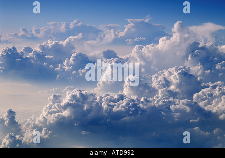 Billowy clouds fill a pale blue sky from above shot from an airplane Stock Photo