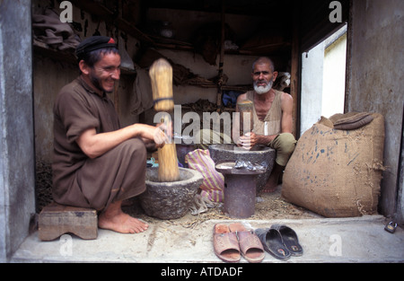 Afghan man pounding tobacco with a mortar pestle Maidan a small Afghani community near Dir Pakistan Stock Photo