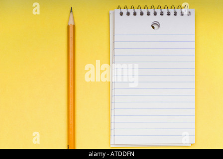 A sharp pencil and a blank notebook on a bright yellow background Stock Photo