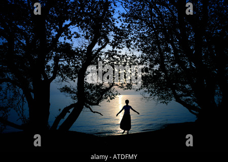 Silhouette of young woman standing by lake Stock Photo