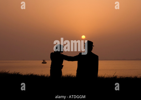 Silhouette of young couple standing by lake Stock Photo