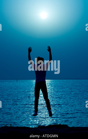 Silhouette of young man jumping by lake Stock Photo