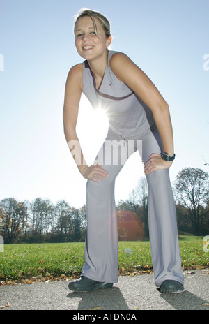 young woman doing stretching exersises and smiling into the camera Stock Photo