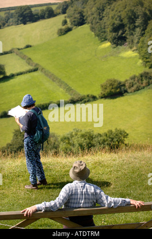 A PAIR OF RAMBLERS CHECK THEIR ORDNANCE SURVEY MAP AND TAKE IN A VIEW OF GLOUCESTERSHIRE UK FROM ULEY BURY TO DOWNHAM HILL AND D Stock Photo