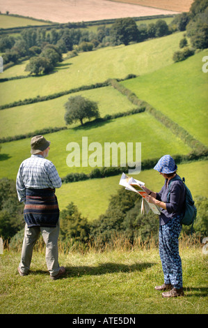 A PAIR OF RAMBLERS CHECK THEIR ORDNANCE SURVEY MAP AND TAKE IN A VIEW OF GLOUCESTERSHIRE UK FROM ULEY BURY TO DOWNHAM HILL AND D Stock Photo