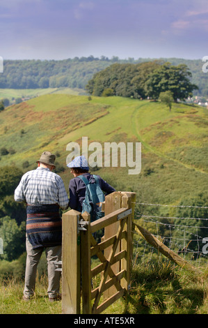 A PAIR OF RAMBLERS TAKE IN A VIEW OF GLOUCESTERSHIRE UK FROM ULEY BURY TO DOWNHAM HILL KNOWN LOCALLY AS SMALLPOX HILL DUE TO ONC Stock Photo