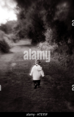 Small child walking on pathway leading away Stock Photo