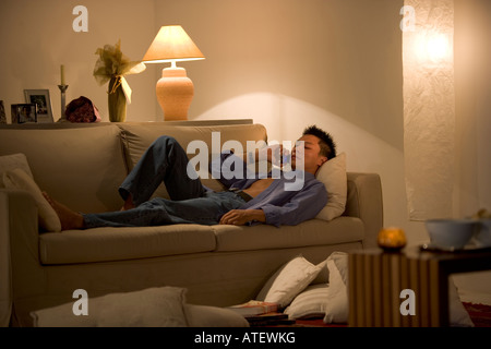 Young man lying on a couch talking on a mobile phone Stock Photo