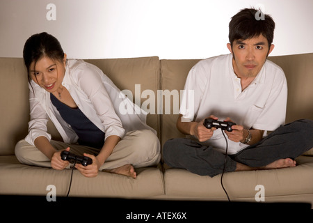 Young couple sitting on a couch playing video games Stock Photo