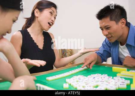 Two young women and a young man playing mahjong Stock Photo