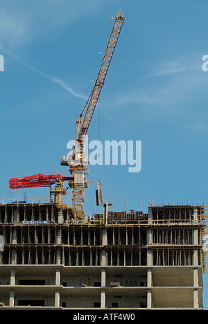 Crane on Top of Building Under Construction Lifting Building Materials Stock Photo