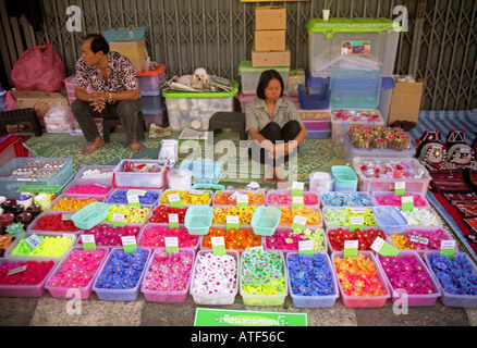 Woman & man sell colourful flower shaped soap & natural products in street Anusan Market Chiang Mai Thailand Southeast Asia